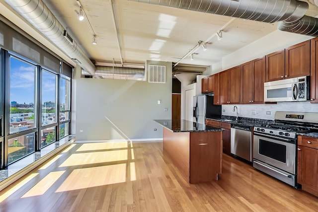 1525 S Sangamon St Unit 609, Chicago, IL 60608 - kitchen with track lighting, stainless steel appliances, a center island, light wood-style flooring, and dark stone countertops