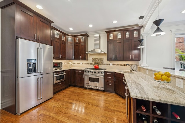 1430 W Diversey Pkwy Unit 1, Chicago, IL 60614 - kitchen featuring high end appliances, wall chimney exhaust hood, a peninsula, dark brown cabinets, and light stone countertops