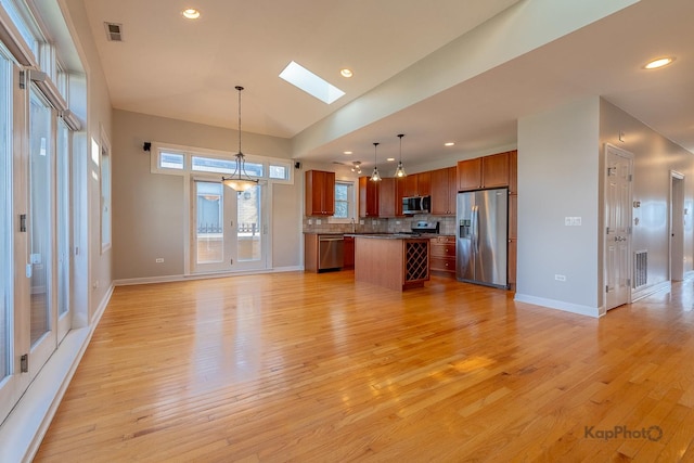 3454 N Ashland Ave Unit 4S, Chicago, IL 60657 - kitchen with stainless steel appliances, a skylight, open floor plan, brown cabinetry, and tasteful backsplash