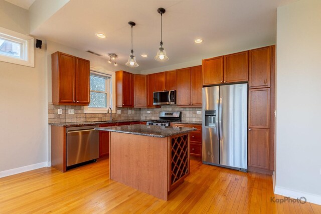 3454 N Ashland Ave Unit 4S, Chicago, IL 60657 - kitchen featuring appliances with stainless steel finishes, decorative backsplash, light wood-style floors, a kitchen island, and decorative light fixtures