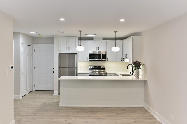 1400 N Elmhurst Rd Unit 310, Mount Prospect, IL 60056 - kitchen with appliances with stainless steel finishes, tasteful backsplash, light countertops, a peninsula, and light wood finished floors