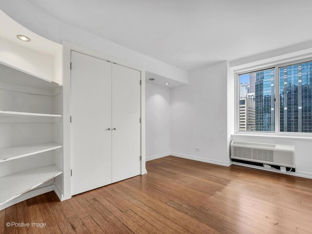 211 E Ohio St Unit 2707, Chicago, IL 60611 - unfurnished bedroom featuring wood-type flooring, a closet, a wall mounted air conditioner, and recessed lighting