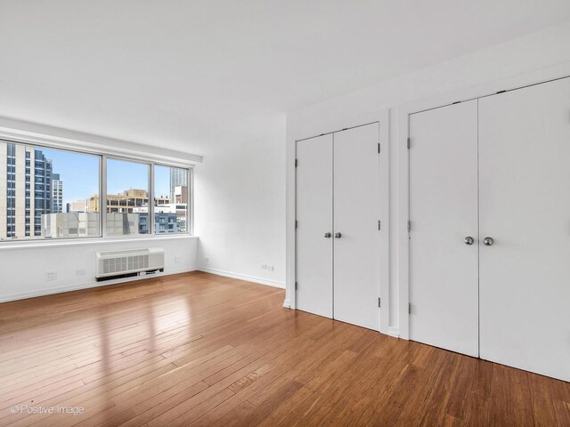 211 E Ohio St Unit 2707, Chicago, IL 60611 - unfurnished bedroom with two closets, wood finished floors, and a wall mounted AC