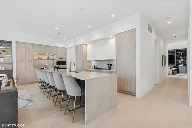 128 S Green St Unit 5Ab, Chicago, IL 60607 - kitchen with modern cabinets, oven, a breakfast bar, a large island, and decorative backsplash