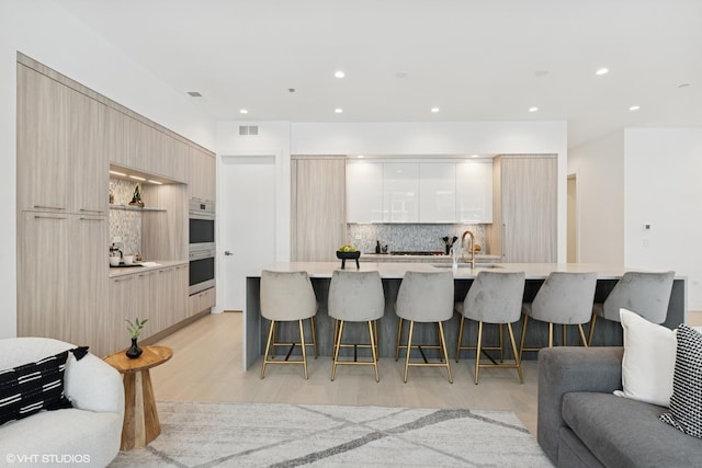 128 S Green St Unit 5Ab, Chicago, IL 60607 - kitchen featuring modern cabinets, tasteful backsplash, a kitchen breakfast bar, light wood-style flooring, and light countertops