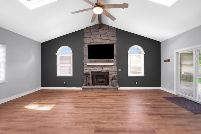 717 Bittersweet Ln, New Lenox, IL 60451 - unfurnished living room featuring a skylight, ceiling fan, a stone fireplace, and wood finished floors