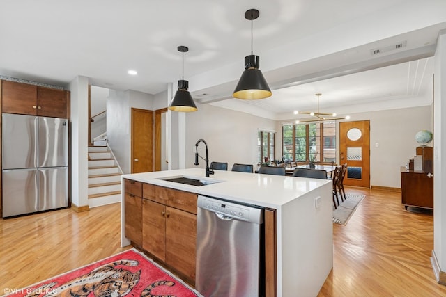 9333 S Oakley Ave, Chicago, IL 60643 - kitchen with stainless steel appliances, light countertops, pendant lighting, an island with sink, and brown cabinetry