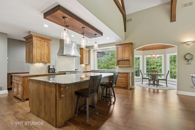 1310 Gavin Ct, Lake Forest, IL 60045 - kitchen featuring wall chimney exhaust hood, a kitchen island, dark wood-style flooring, decorative light fixtures, and brown cabinetry