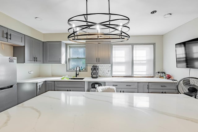 4636 S Keating Ave, Chicago, IL 60632 - kitchen with gray cabinets, a chandelier, light stone counters, pendant lighting, and tasteful backsplash