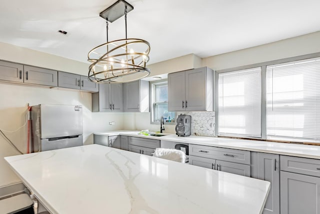 4636 S Keating Ave, Chicago, IL 60632 - kitchen featuring gray cabinets, freestanding refrigerator, a chandelier, light stone counters, and decorative light fixtures