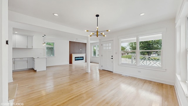 15230 State St, South Holland, IL 60473 - unfurnished living room with a chandelier, light wood finished floors, healthy amount of natural light, a glass covered fireplace, and recessed lighting