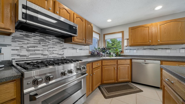 70 Delburne Dr, Davis, IL 61019 - kitchen with stainless steel appliances, dark countertops, tasteful backsplash, brown cabinets, and a textured ceiling