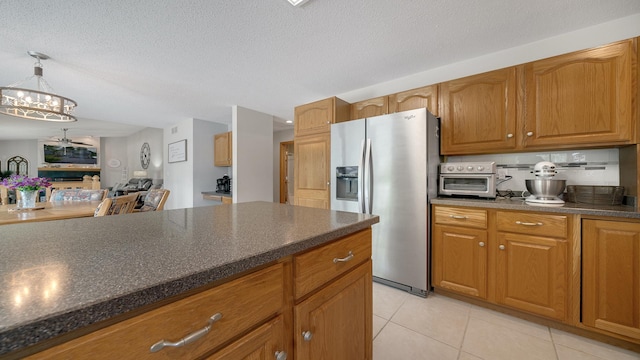 70 Delburne Dr, Davis, IL 61019 - kitchen featuring stainless steel refrigerator with ice dispenser, light tile patterned floors, dark countertops, brown cabinets, and a chandelier