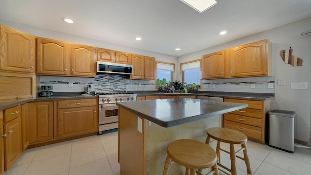70 Delburne Dr, Davis, IL 61019 - kitchen with stainless steel appliances, dark countertops, backsplash, a breakfast bar area, and a kitchen island