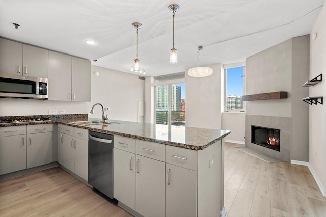 1515 S Prairie Ave Unit 715, Chicago, IL 60605 - kitchen with appliances with stainless steel finishes, a peninsula, light wood-style floors, dark stone counters, and a fireplace with flush hearth