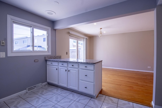 9135 Hollyberry Ave, Des Plaines, IL 60016 - kitchen featuring white cabinetry, a peninsula, a chandelier, light tile patterned floors, and light stone counters