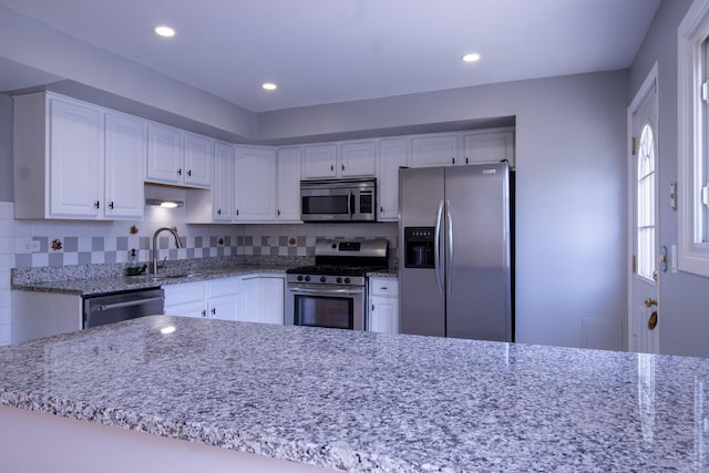 9135 Hollyberry Ave, Des Plaines, IL 60016 - kitchen featuring appliances with stainless steel finishes, white cabinets, light stone countertops, tasteful backsplash, and recessed lighting