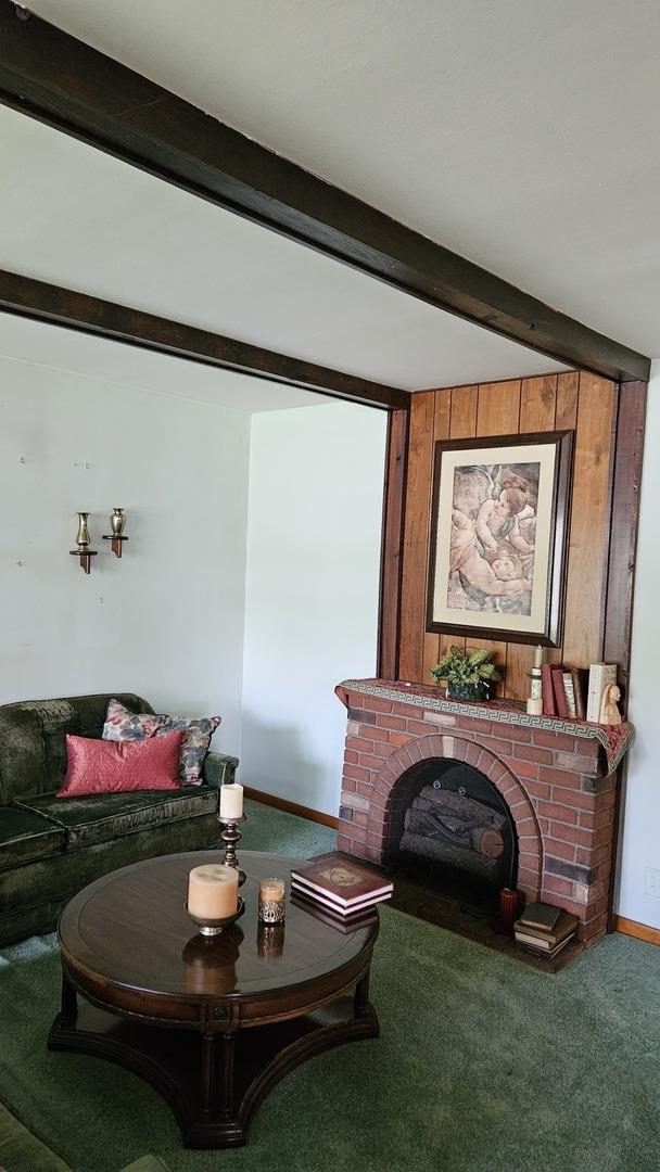 14357 Kenton Ave, Midlothian, IL 60445 - carpeted living room featuring beam ceiling, a brick fireplace, and wooden walls