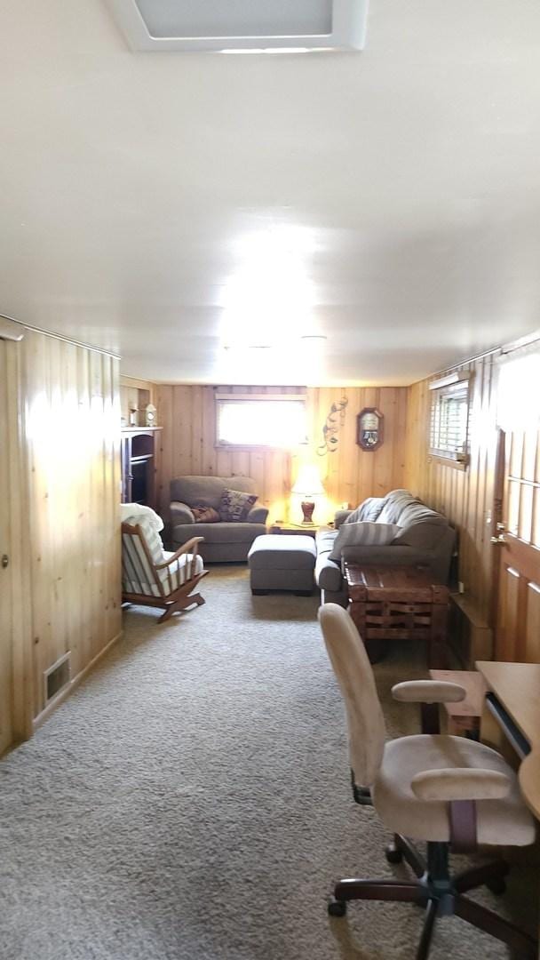 14357 Kenton Ave, Midlothian, IL 60445 - living room with wood walls, healthy amount of natural light, and carpet flooring