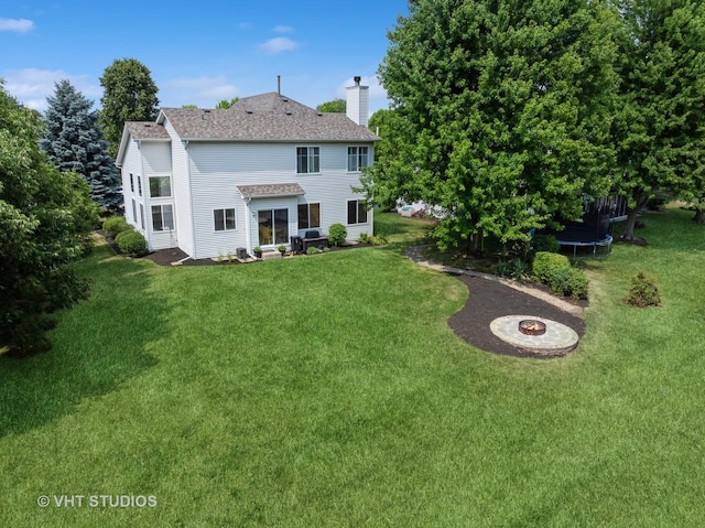 134 S Hankes Rd, Aurora, IL 60506 - back of house with a trampoline, a chimney, a yard, and a fire pit