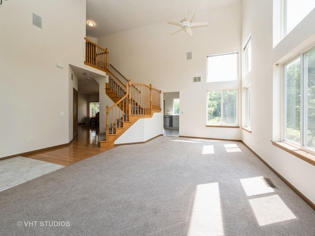 134 S Hankes Rd, Aurora, IL 60506 - unfurnished living room featuring carpet, healthy amount of natural light, stairs, a towering ceiling, and a ceiling fan