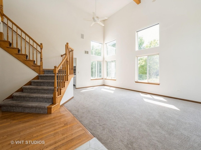 134 S Hankes Rd, Aurora, IL 60506 - unfurnished living room featuring stairway, ceiling fan, a towering ceiling, and carpet