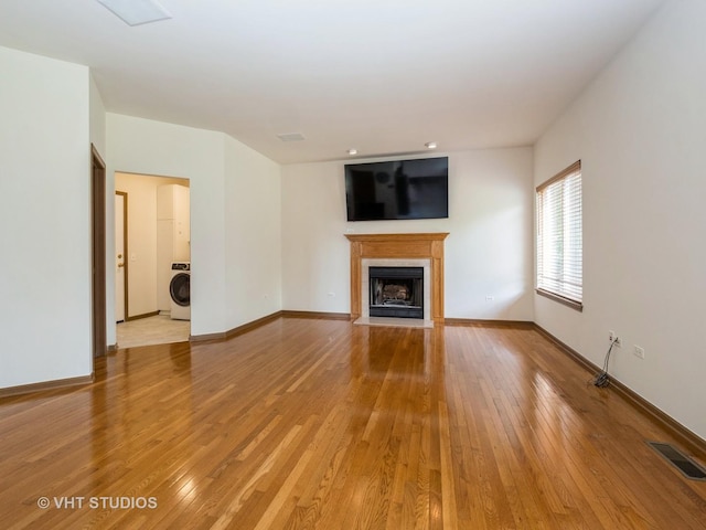 134 S Hankes Rd, Aurora, IL 60506 - unfurnished living room with washer / dryer, a fireplace with flush hearth, and light wood-type flooring