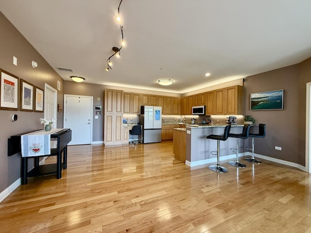 160 S River St Unit 204, Aurora, IL 60506 - kitchen featuring freestanding refrigerator, stainless steel microwave, a peninsula, a kitchen breakfast bar, and brown cabinetry