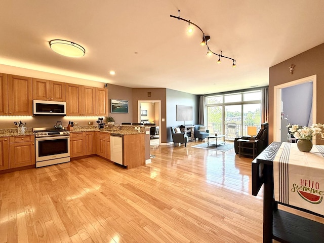 160 S River St Unit 204, Aurora, IL 60506 - kitchen with stainless steel appliances, a peninsula, open floor plan, light stone countertops, and light wood finished floors