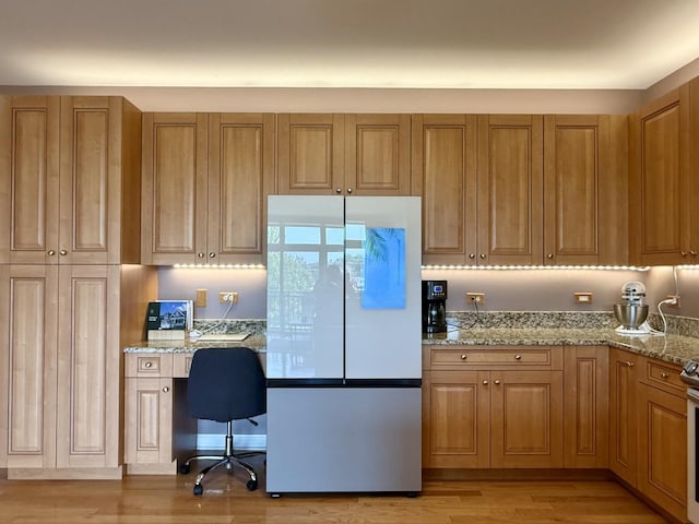 160 S River St Unit 204, Aurora, IL 60506 - kitchen with freestanding refrigerator, built in study area, light stone countertops, and brown cabinets
