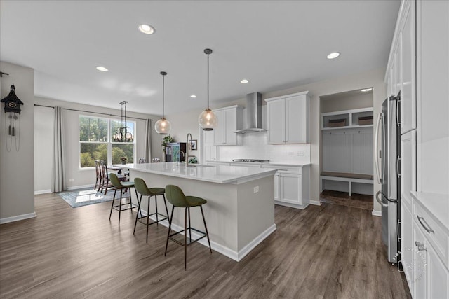 340 Hamilton Rd, Saint Charles, IL 60175 - kitchen featuring wall chimney exhaust hood, a breakfast bar, a kitchen island with sink, white cabinetry, and tasteful backsplash