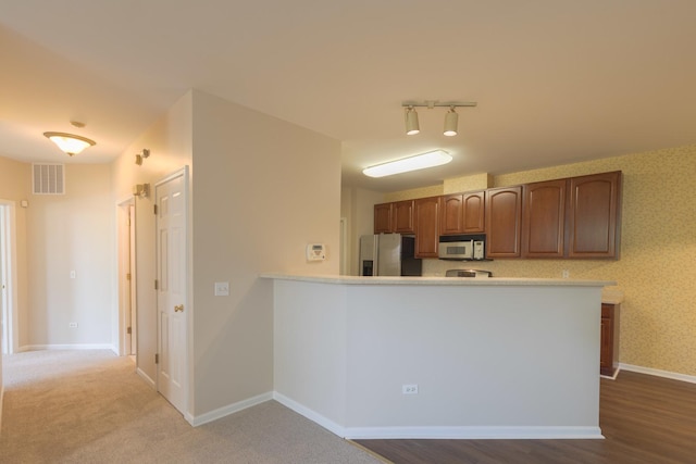 8126 Concord Ln Unit A, Justice, IL 60458 - kitchen featuring stainless steel refrigerator with ice dispenser, light countertops, a peninsula, and brown cabinetry