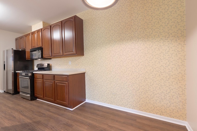 8126 Concord Ln Unit A, Justice, IL 60458 - kitchen featuring appliances with stainless steel finishes, dark wood finished floors, light countertops, brown cabinetry, and wallpapered walls