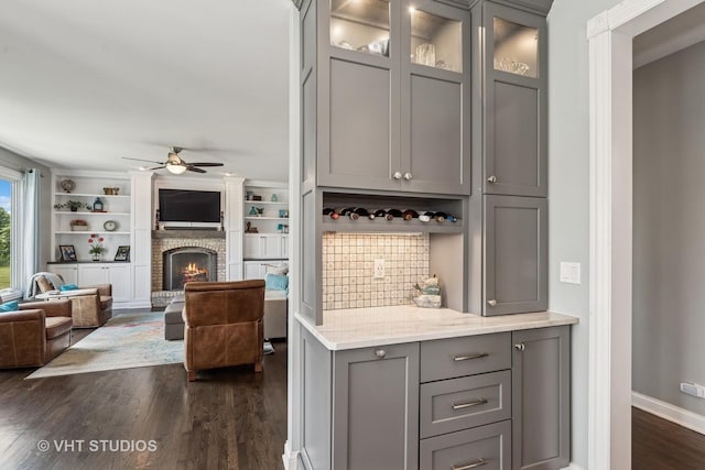 2 E Prairie Ct, Hawthorn Woods, IL 60047 - bar area featuring dark wood-style flooring, ceiling fan, a brick fireplace, and tasteful backsplash