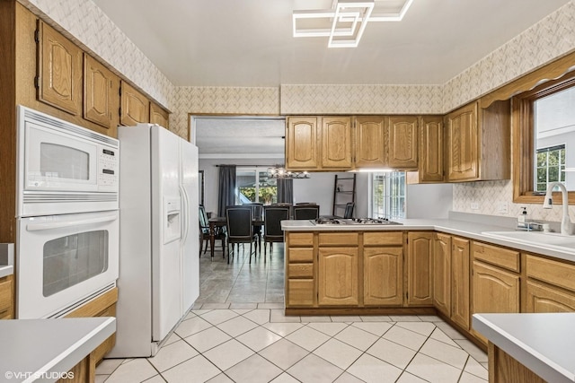 2215 Yeoman St, Waukegan, IL 60087 - kitchen with white appliances, wallpapered walls, light countertops, brown cabinets, and a peninsula