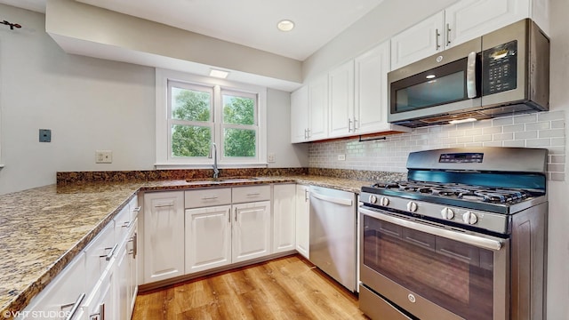 4265 Portage Ln, Hoffman Estates, IL 60192 - kitchen featuring stainless steel appliances, light wood-style floors, white cabinets, decorative backsplash, and recessed lighting
