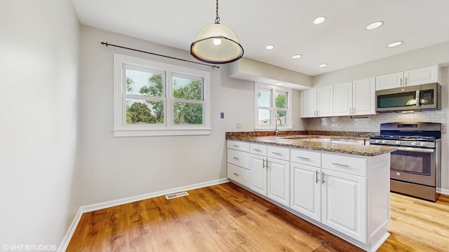 4265 Portage Ln, Hoffman Estates, IL 60192 - kitchen with appliances with stainless steel finishes, light wood finished floors, white cabinets, decorative backsplash, and recessed lighting