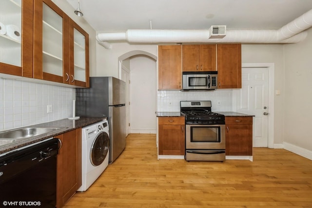1729 W Erie St Unit 3N, Chicago, IL 60622 - kitchen featuring appliances with stainless steel finishes, washer / dryer, light wood-style flooring, tasteful backsplash, and brown cabinets