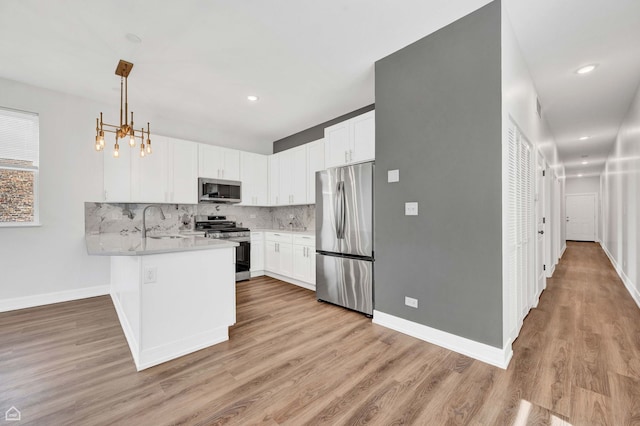 4435 S Prairie Ave, Chicago, IL 60653 - kitchen featuring stainless steel appliances, a peninsula, backsplash, light wood-style floors, and recessed lighting