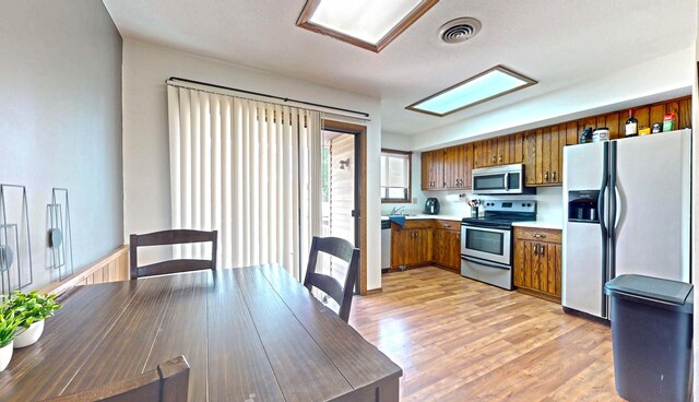1301 Clifford Ave Unit 8, Urbana, IL 61802 - kitchen with stainless steel appliances, brown cabinetry, light countertops, and light wood finished floors