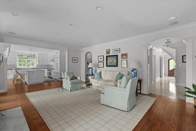 1111 Seneca Rd, Wilmette, IL 60091 - living area with arched walkways, crown molding, ornate columns, wood finished floors, and recessed lighting