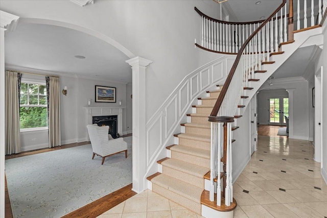 1111 Seneca Rd, Wilmette, IL 60091 - staircase with decorative columns, crown molding, healthy amount of natural light, arched walkways, and tile patterned floors