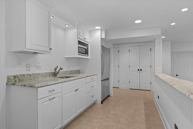 1111 Seneca Rd, Wilmette, IL 60091 - kitchen featuring stainless steel microwave, freestanding refrigerator, white cabinets, recessed lighting, and light stone countertops