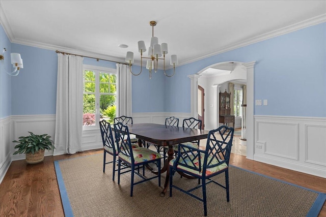1111 Seneca Rd, Wilmette, IL 60091 - dining space with arched walkways, ornate columns, a chandelier, wainscoting, and wood finished floors