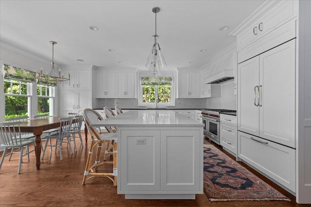 1111 Seneca Rd, Wilmette, IL 60091 - kitchen featuring high end appliances, decorative backsplash, white cabinetry, a kitchen island, and ornamental molding