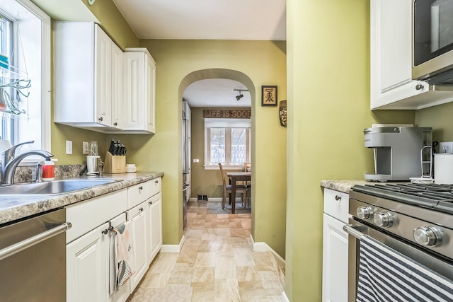 7805 W Farragut Ave, Chicago, IL 60656 - kitchen with appliances with stainless steel finishes, arched walkways, white cabinets, and light countertops