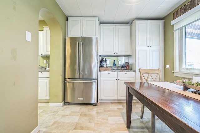 7805 W Farragut Ave, Chicago, IL 60656 - kitchen featuring high quality fridge, white cabinetry, arched walkways, and light stone countertops