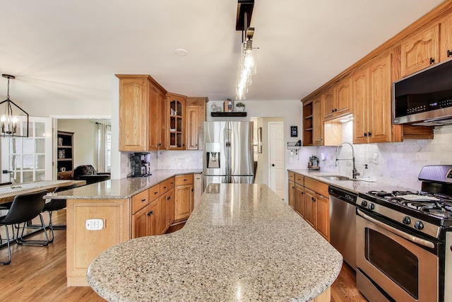 115 Circle Dr W, Montgomery, IL 60538 - kitchen with appliances with stainless steel finishes, light stone counters, decorative backsplash, glass insert cabinets, and a chandelier