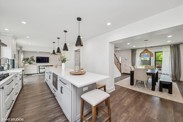 1227 Timber Dr, Elk Grove Village, IL 60007 - kitchen featuring dark wood-style flooring, white cabinetry, light countertops, a breakfast bar, and a center island