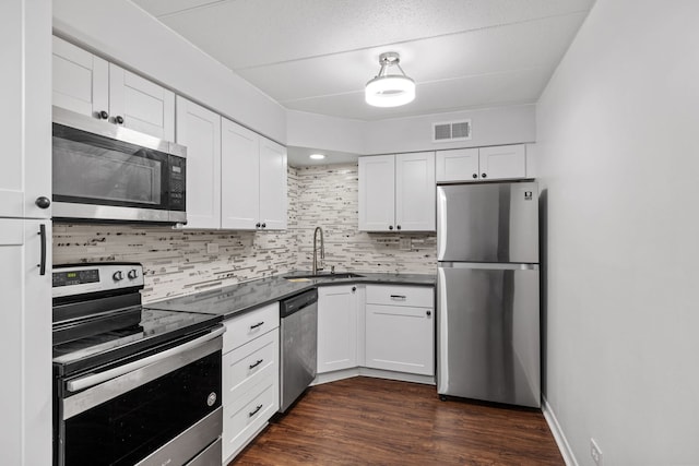 491 Timber Ridge Dr Unit 104, Carol Stream, IL 60188 - kitchen with appliances with stainless steel finishes, tasteful backsplash, dark countertops, white cabinets, and dark wood-style flooring